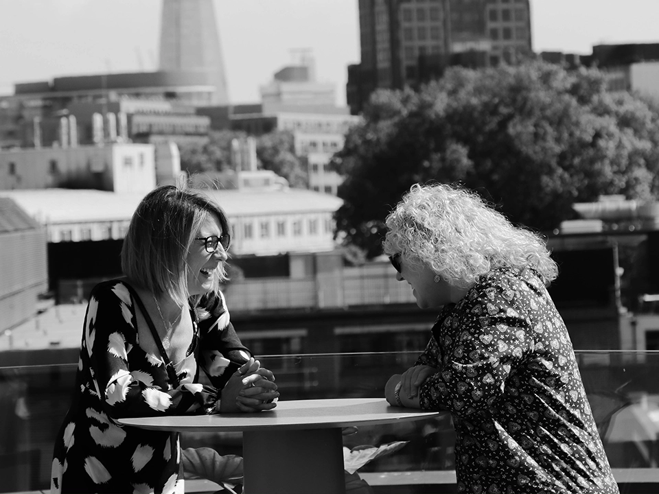 Two professional women talking on a rooftop in London